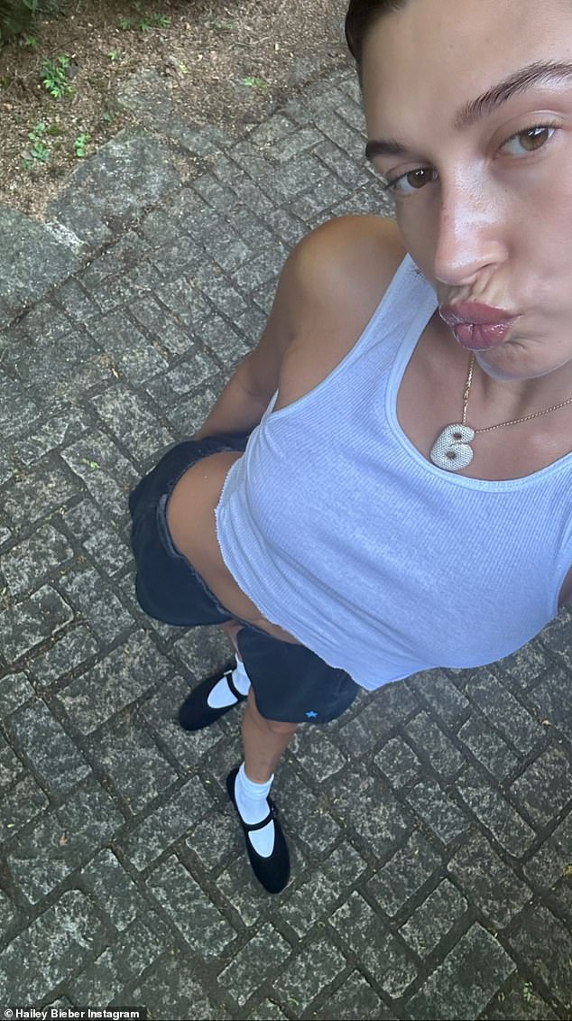 Chic schoolgirl: Hailey showed off her abs in several looks and pursed her lips in another selfie, where she wore a white tank top, gray shorts and black Mary Jane shoes with white socks