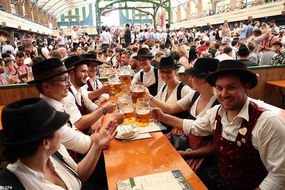 Revelers dressed in lederhosen enjoy beer steins on the second day of Oktoberfest