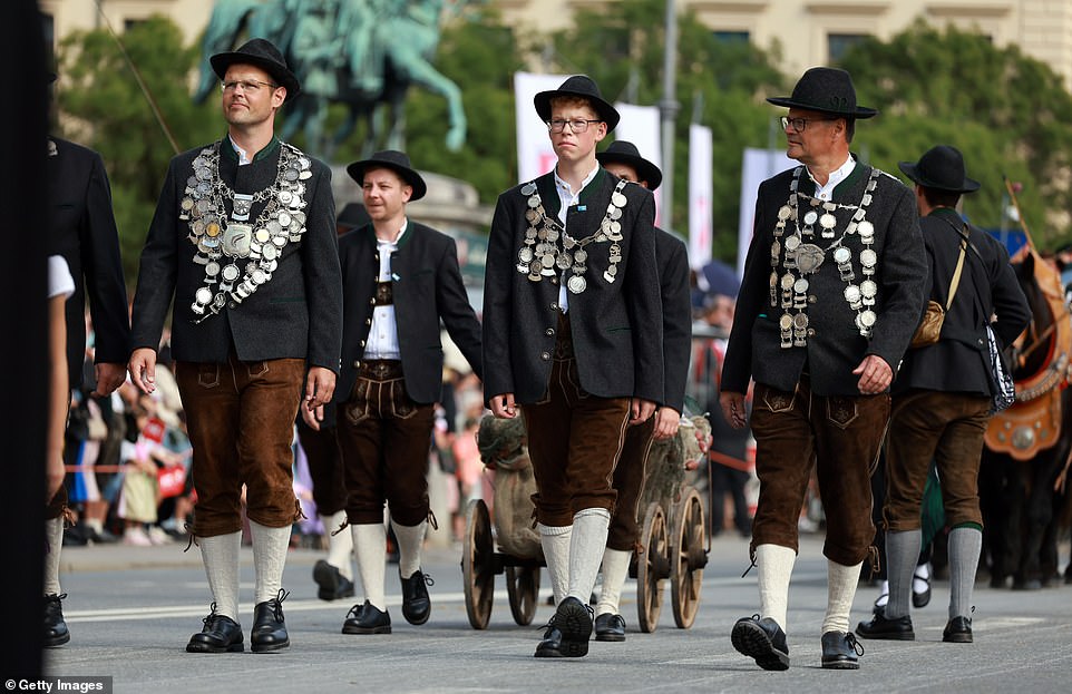 Members of a group wearing traditional costumes stroll along the road during the costume parade earlier today