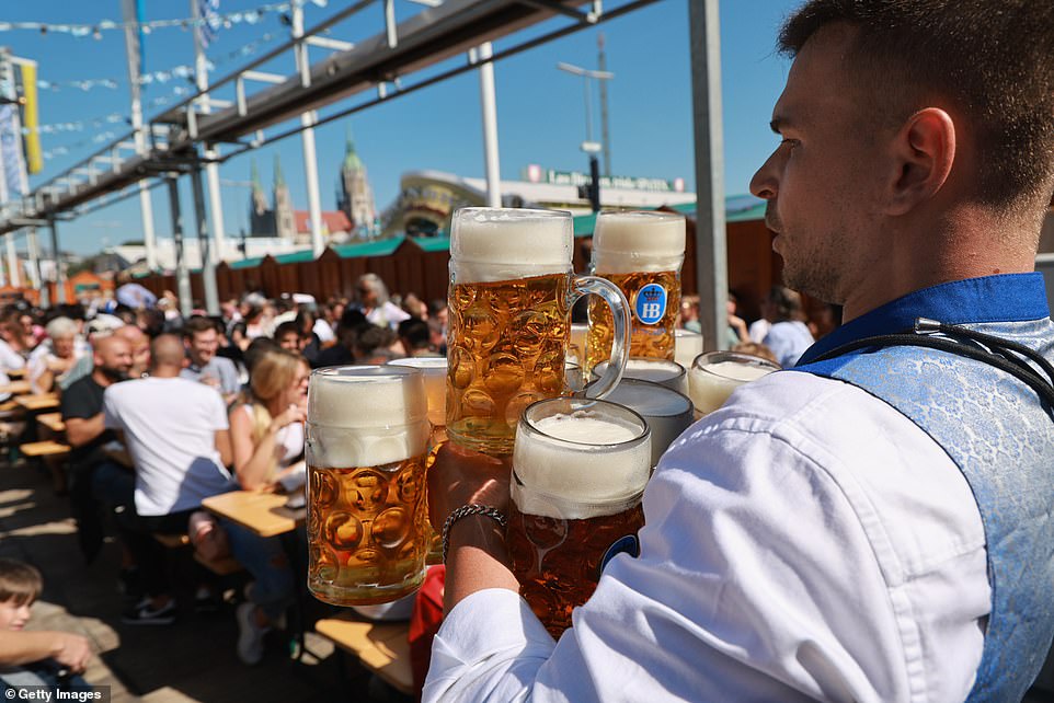 A waiter in the Hofbraeu tent balances a dozen one-liter beer mugs as he carries them to a table