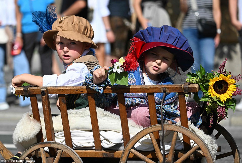 Children sit in a pushcart during the costume parade at the 2023 Oktoberfest