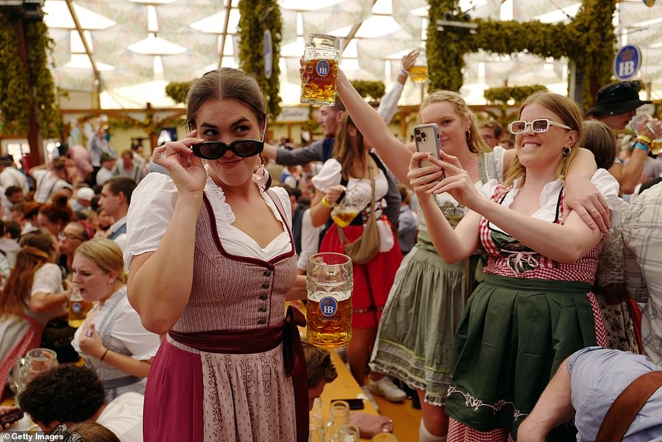 Revelers drink beer from traditional beer steins in the Hofbraeu tent