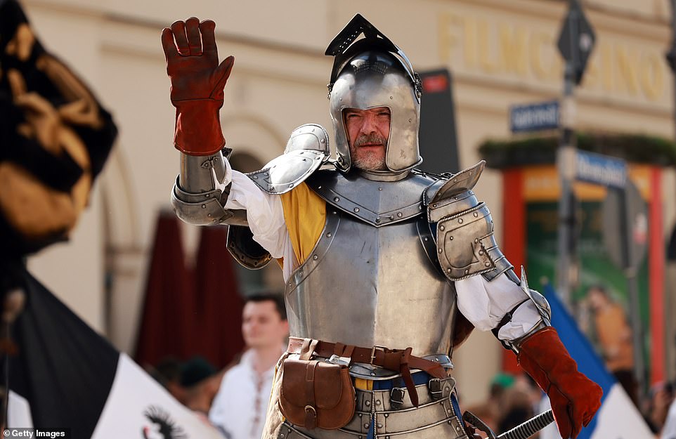 A man dressed in armor waves to the crowd during the shooter's parade