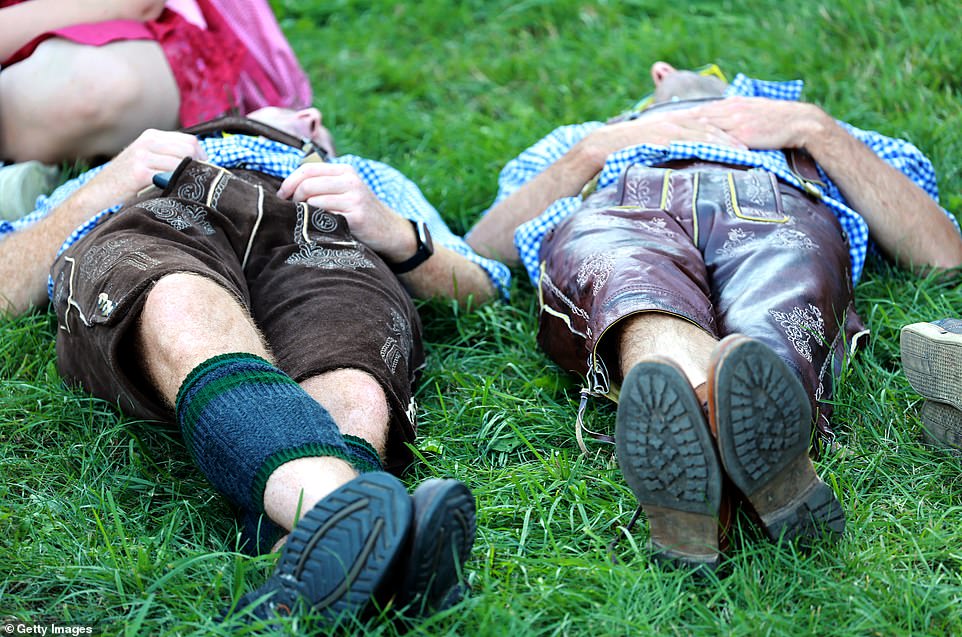 Revelers dressed in lederhosen are shown taking a rest before the beer drinking continues