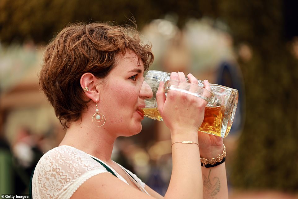 A young woman sips her beer from a famous one-liter beer mug