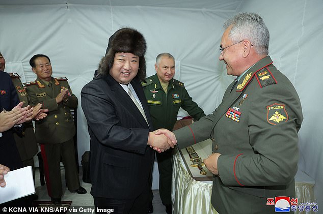 North Korean leader Kim Jong Un (L) shakes hands with Russian Defense Minister Sergei Shoigu (R) after receiving a gift during their lunch during a visit to Vladivostok port on September 17