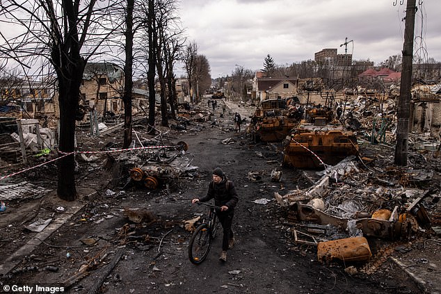 A man pushes his bicycle through rubble and destroys Russian military vehicles on the street on April 6, 2022 in Bucha, Ukraine