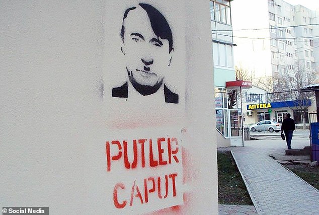 Graffiti is seen depicting Putin with a Hitler moustache