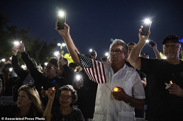 Miguel Ruiz, center, and his wife Sara, seated, attend a vigil in Palmdale, California, for Los Angeles County Deputy Sheriff Clinkunbroomer at the Palmdale Sheriff's Station on Sunday