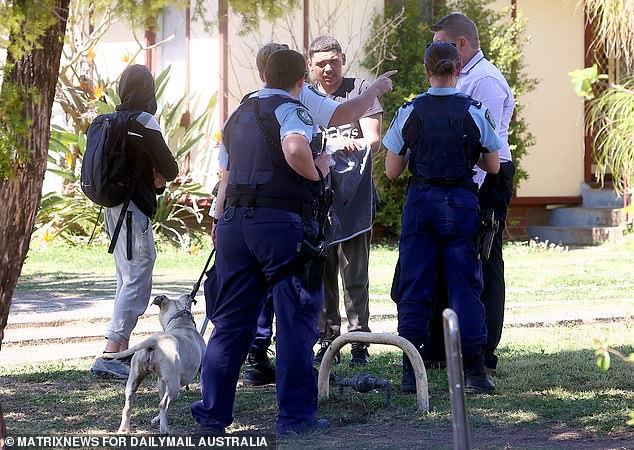 Police gather at the scene where an escaped pit bull terrier brutally bit a mother and her son