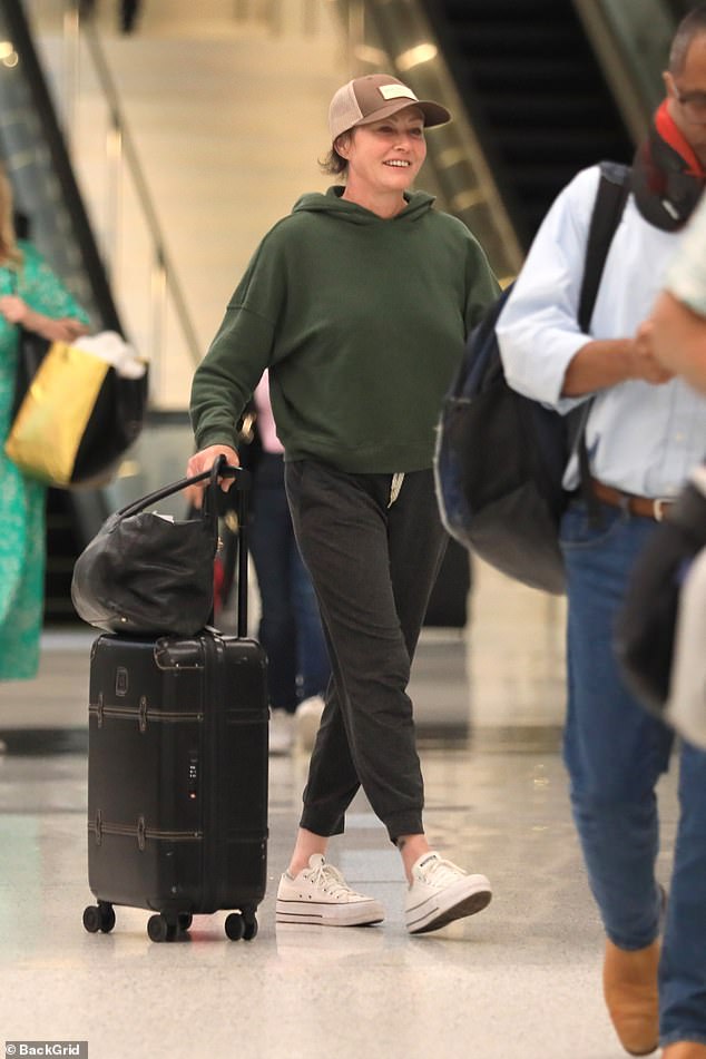 Comfortable: The Beverly Hills 90210 alum, 52, smiled and looked happy as she rolled her luggage through the busy terminal