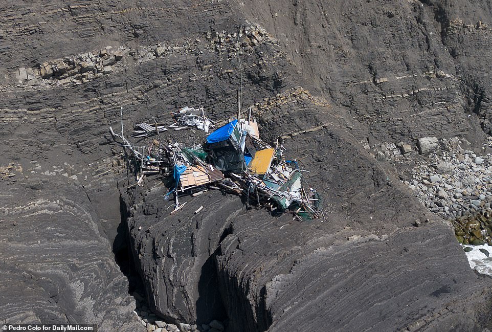 Photos show the wreckage of the driftwood house near Pacifica, California, with the roof torn open and the blue tarp exposed