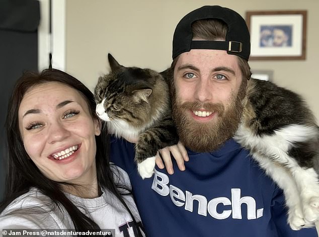 Natalie and her now fiancé are all smiles as they cuddle with their fluffy cat