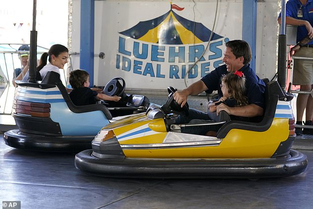 The couple often takes their children on campaign trips;  above Ron DeSantis laughs as he rides in a bumper car with his daughter Madison as they hit another car driven by Casey DeSantis, left, and their son Mason at the Iowa State Fair