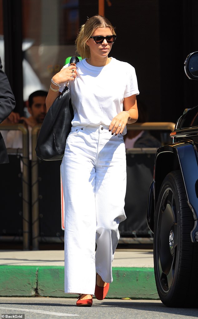 Casual chic: The 24-year-old model wore a white T-shirt and loose white jeans as she dined in the posh area