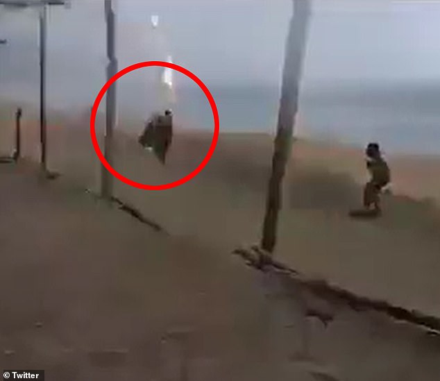 A merchant (circled) is seen walking on a beach in Mexico just as lightning struck and killed a woman meters away from him, moments before he was also shocked and later died in a hospital