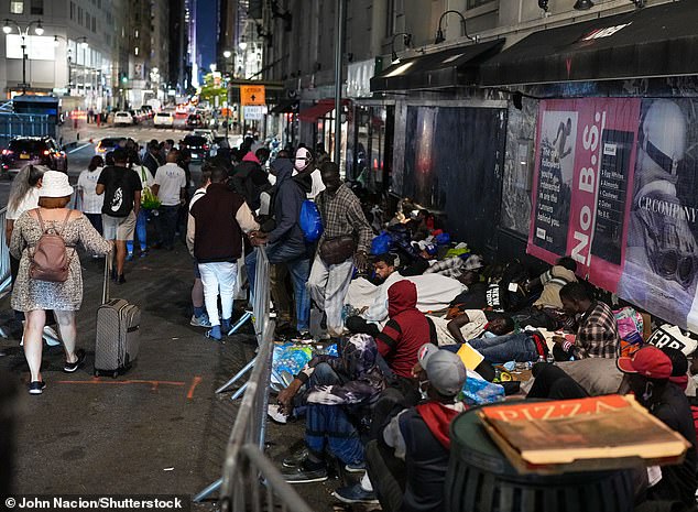 Asylum seekers, deprived of a hotel room, line the sidewalk of the Roosevelt Hotel