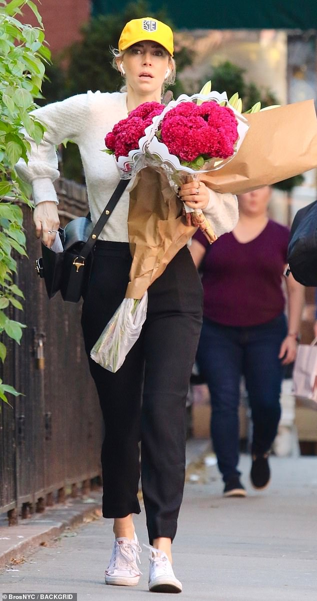 Casual look: She donned a white crew-neck sweater and black drawstring pants as she purchased several bouquets of flowers.