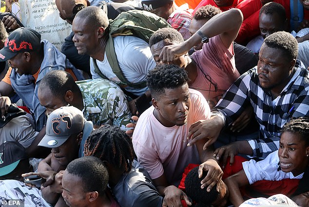 The migrants, most of them from Haiti, are caught in the middle of a stampede moments after a security barricade was toppled outside the Mexican Refugee Aid Commission in Tapachula on Monday.