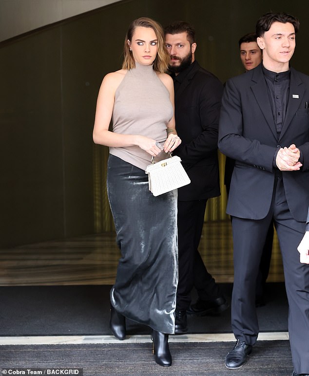 Turning heads: She added inches to her figure with a pair of knee-high black leather boots and carried her belongings in a sleek white woven handbag.