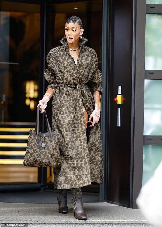 Looking good: The model carried a matching patterned handbag and enhanced her already imposing figure with brown heeled knee-high boots.