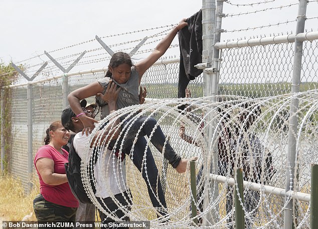 A group of migrants from Colombia, Honduras and Guatemala successfully scale a border fence with the United States, south of Eagle Pass.