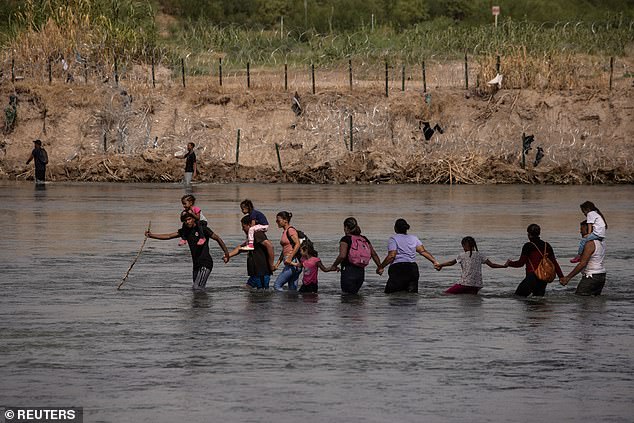 Migrants navigate the Rio Grande River toward a U.S. port of entry at Eagle Pass, Texas, on Friday.