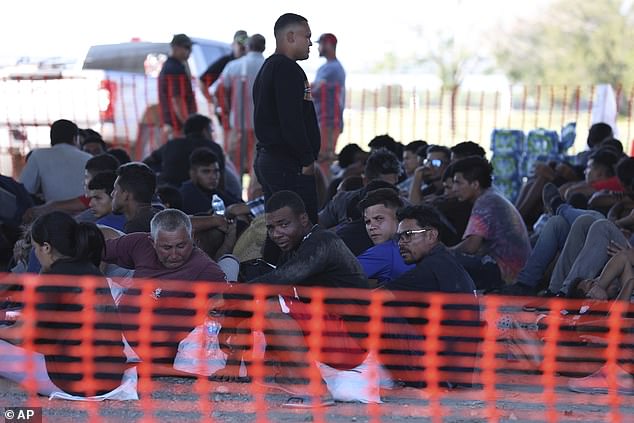 Migrants sit under the bridge in Eagle Pass on Wednesday, awaiting processing