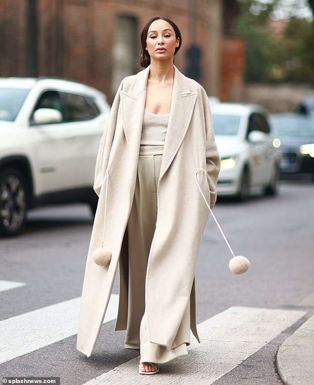 Chic: Actress Cara Santana looked effortlessly stylish in a cream long coat worn over a deep knit top and sage pants