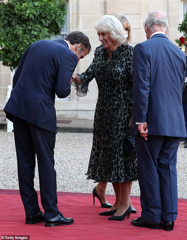 Queen Camilla (pictured, center) smiled as the French President (pictured, left) greeted her with a kiss on the hand