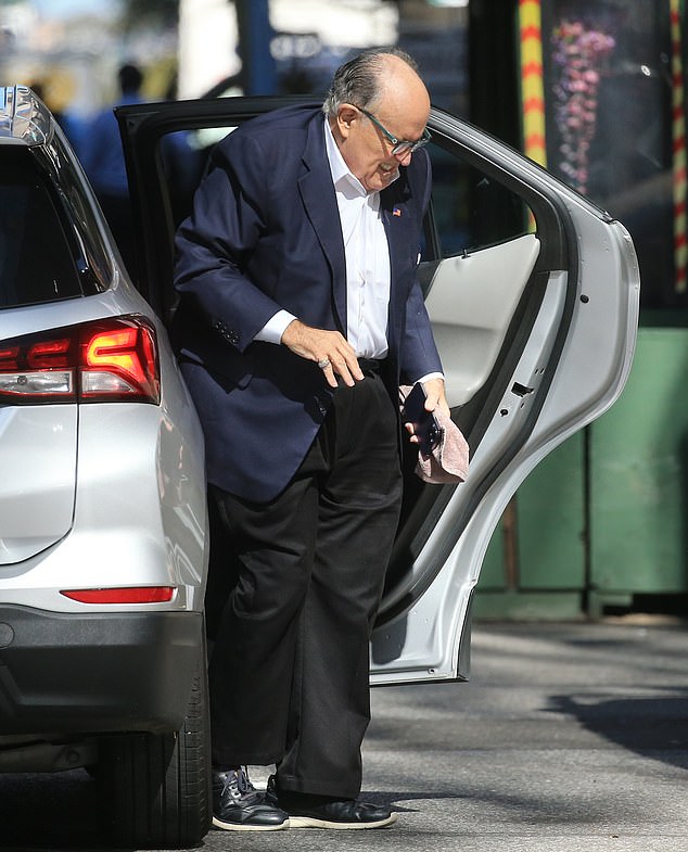 In footage obtained exclusively by DailyMail.com, Giuliani is seen getting out of a taxi with a towel and an iPhone in his hand