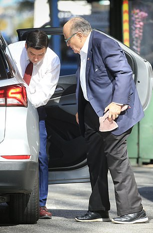 Giuliani and his assistant get out of a taxi in central New York on Thursday