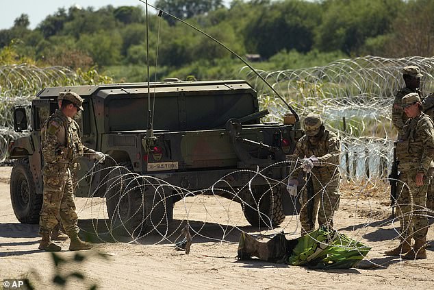 The Texas National Guard is seen laying the razor wire on Thursday