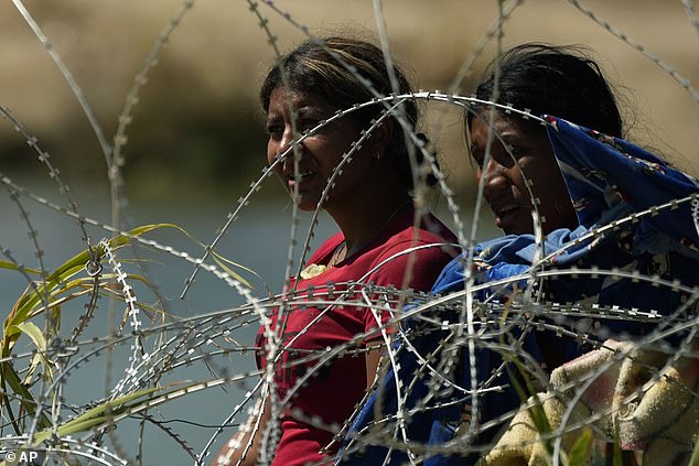 Migrants are seen looking at the barbed wire in Eagle Pass, Texas