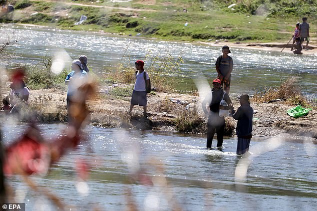 Migrants are seen wading through the Rio Grande near Eagle Pass on Thursday