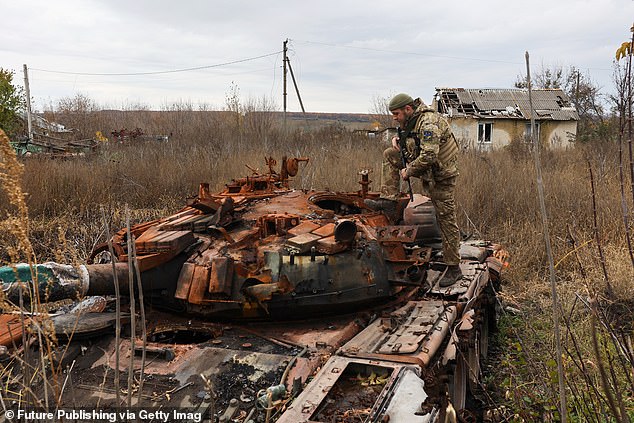 A Ukrainian soldier examines a destroyed Russian tank in the village of Tsupivka in the north of Kharkov region, northeastern Ukraine