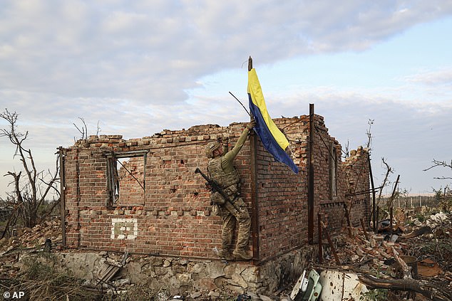 A commander of an assault unit of the 3rd Assault Brigade with the call sign 'Fedia' raises the Ukrainian flag as a symbol of the liberation of the frontline village of Andriivka, Donetsk region, Ukraine, Saturday, September 16, 2023