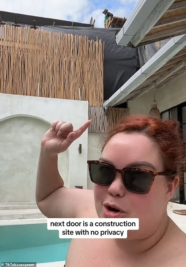 Sam (pictured pointing to the construction workers) said gravel fell on her while she was swimming and she couldn't take videos because of the noise