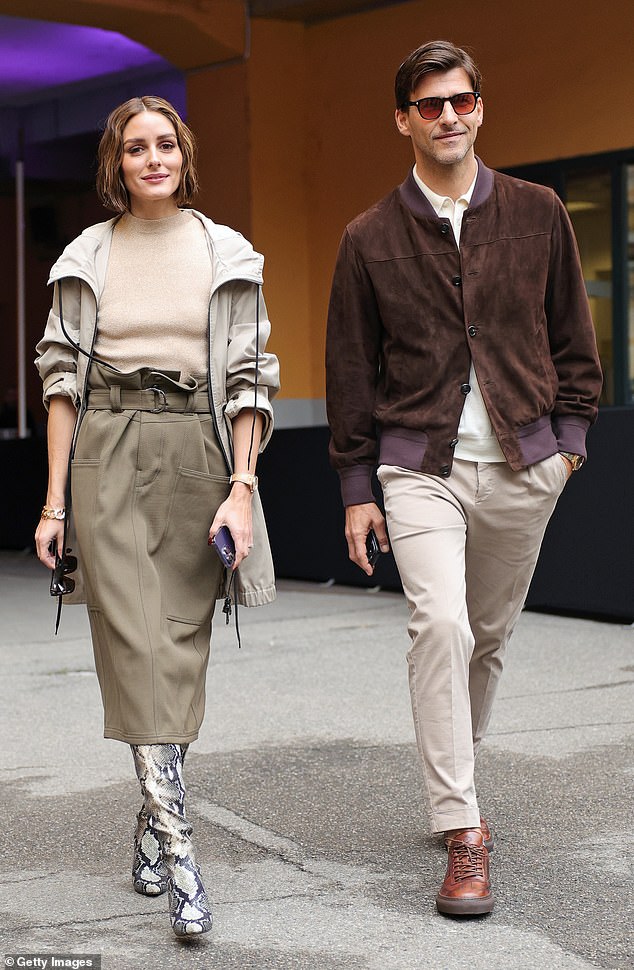 Arrival: The fashionista kept it casual with a stone raincoat, but amped up the glamor with a pair of knee-high snake print heeled boots (pictured with Johannes Huebl)