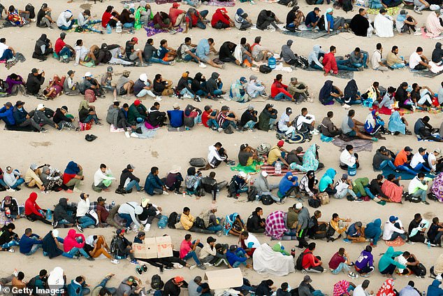 In an aerial view, migrants are seen grouped together as they await processing on the Ciudad Juarez side of the border on September 21, 2023 in El Paso, Texas