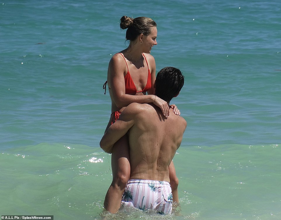 Fun in the sun: Hannah is held by her model fiance Adam Woolard and her long legs hang on either side of his back