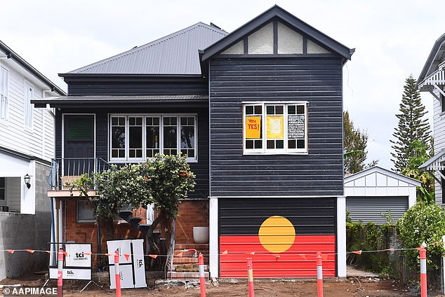 The house on the right, painted black, has turned the garage door into an Aboriginal flag and has 'Vote Yes' posters in the windows