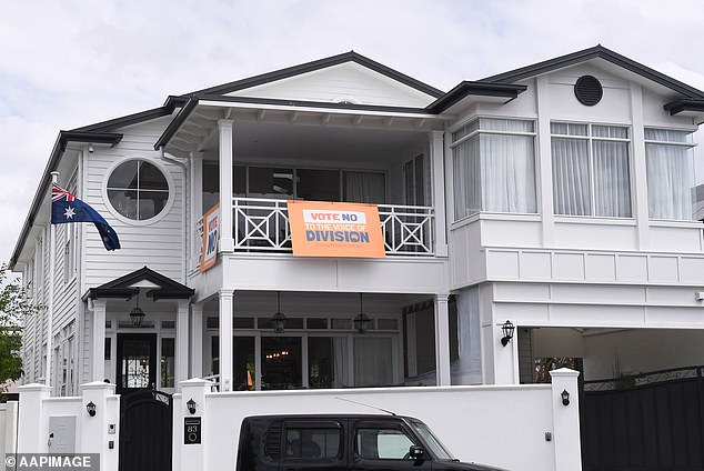 Meanwhile, just next door, a stark white house with an Australian flag and a 'Vote No to Division' poster hanging from its second-floor balcony.