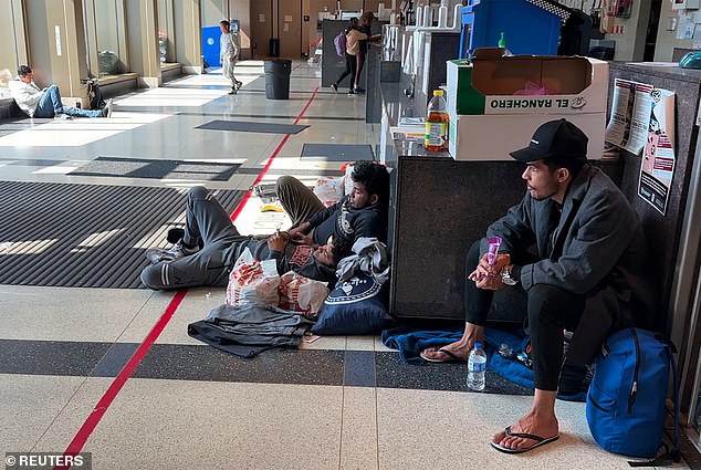 Some migrants are pictured sitting on the floor of a police station awaiting temporary shelter