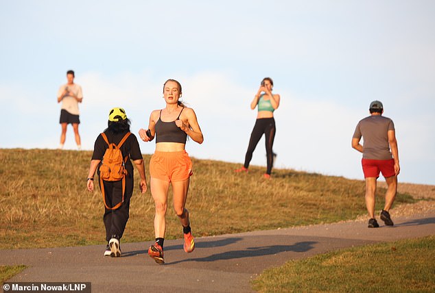 Joggers go for a morning run on Primrose Hill in North London shortly after sunrise today in September 2023