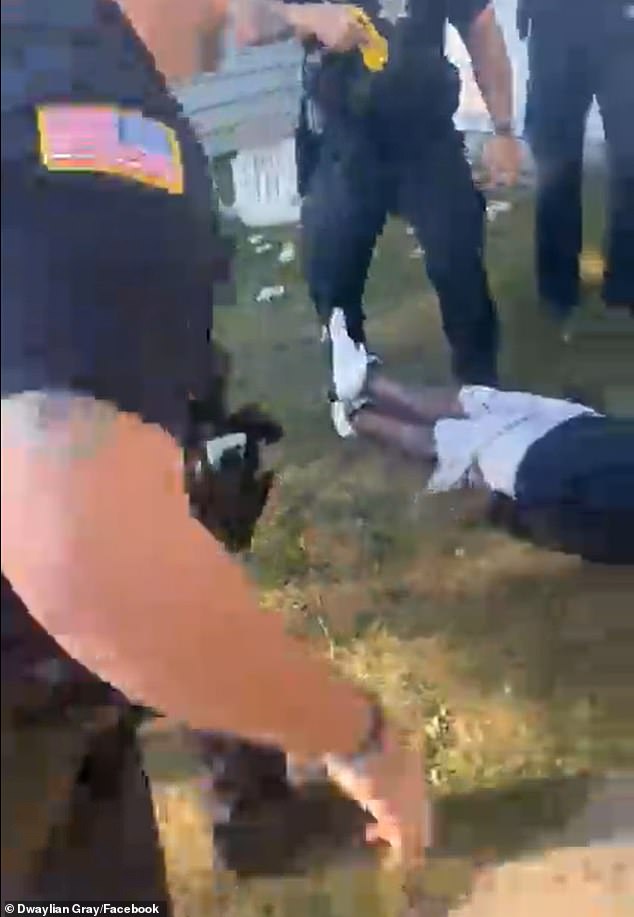 One of the officers uses a taser on him and the suspect falls to the ground.  “Give him handcuffs now,” an officer shouts as four people hold him back