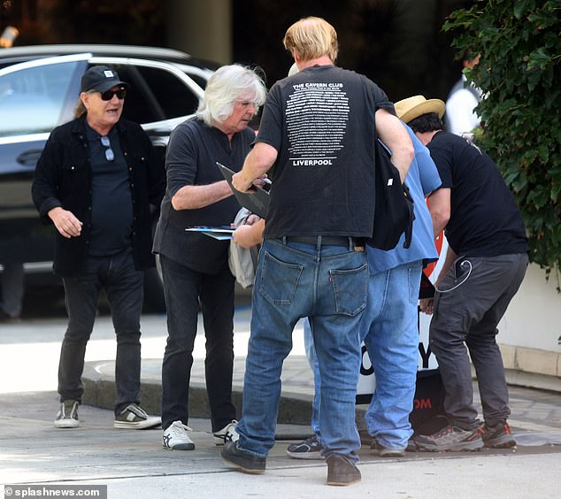 Dressed entirely in black, the AC/DC duo walked straight towards a group of gentlemen carrying stacks of old rock records recorded by the Australian rock band