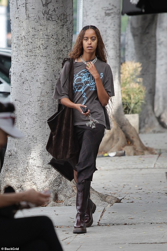 Malia wore a dark gray graphic T-shirt, a long black skirt and dark brown mid-calf boots during the outing