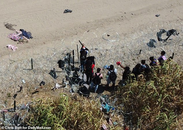 On Wednesday, he accused President Biden of ordering holes to be cut in the wire before ordering local officials to replace and double it.  The photo shows migrants trying to find a way through the thick wire on Friday