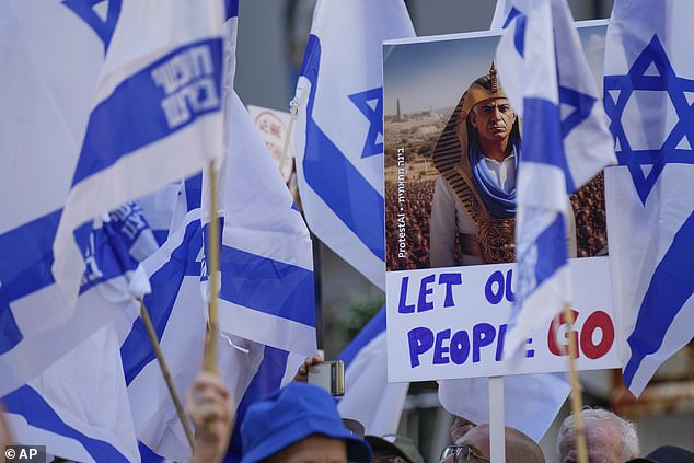 A protester holds up a sign depicting Benjamin Netanyahu as the Pharaoh with the message: 'Let our people go'